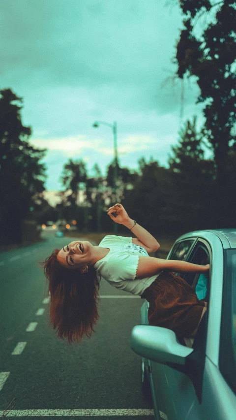 a woman leaning out the window of a car, an album cover, inspired by Elsa Bleda, pexels contest winner, happening, head bent back in laughter, 15081959 21121991 01012000 4k, girl with brown hair, woman with red hair