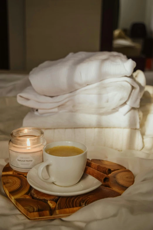 a cup of coffee sitting on top of a bed, spa, gold and white robes, cinnamon, soft white glow