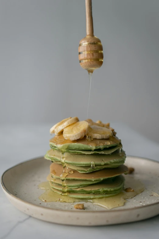 a stack of pancakes sitting on top of a white plate, unsplash, beautiful green liquid, clumps of bananas, honey dripping from ceiling, pastel green