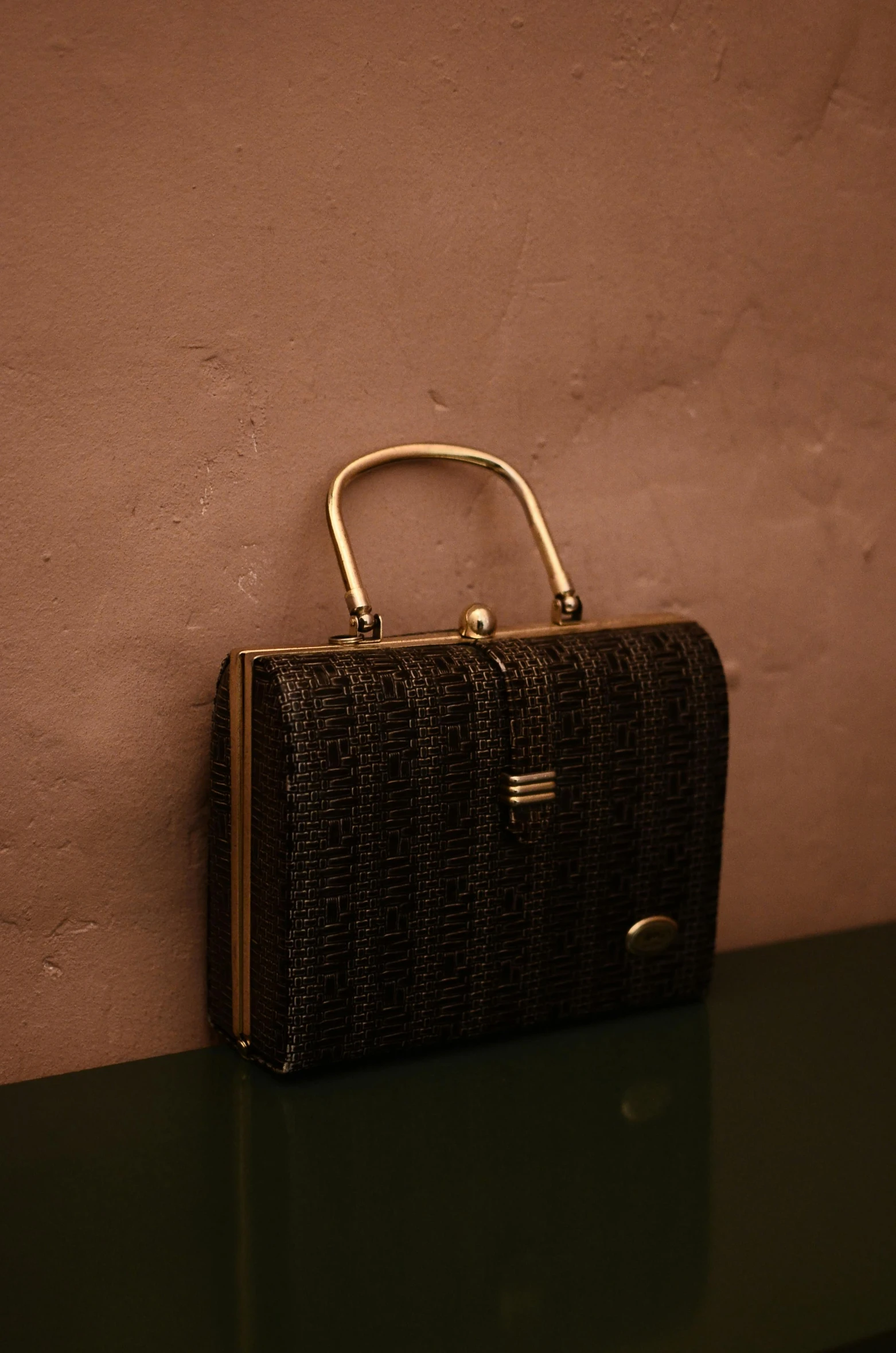 a black purse sitting on top of a table, an album cover, by Carlo Martini, unsplash, baroque, straw, 1 9 5 0 s, bangalore, briefcase