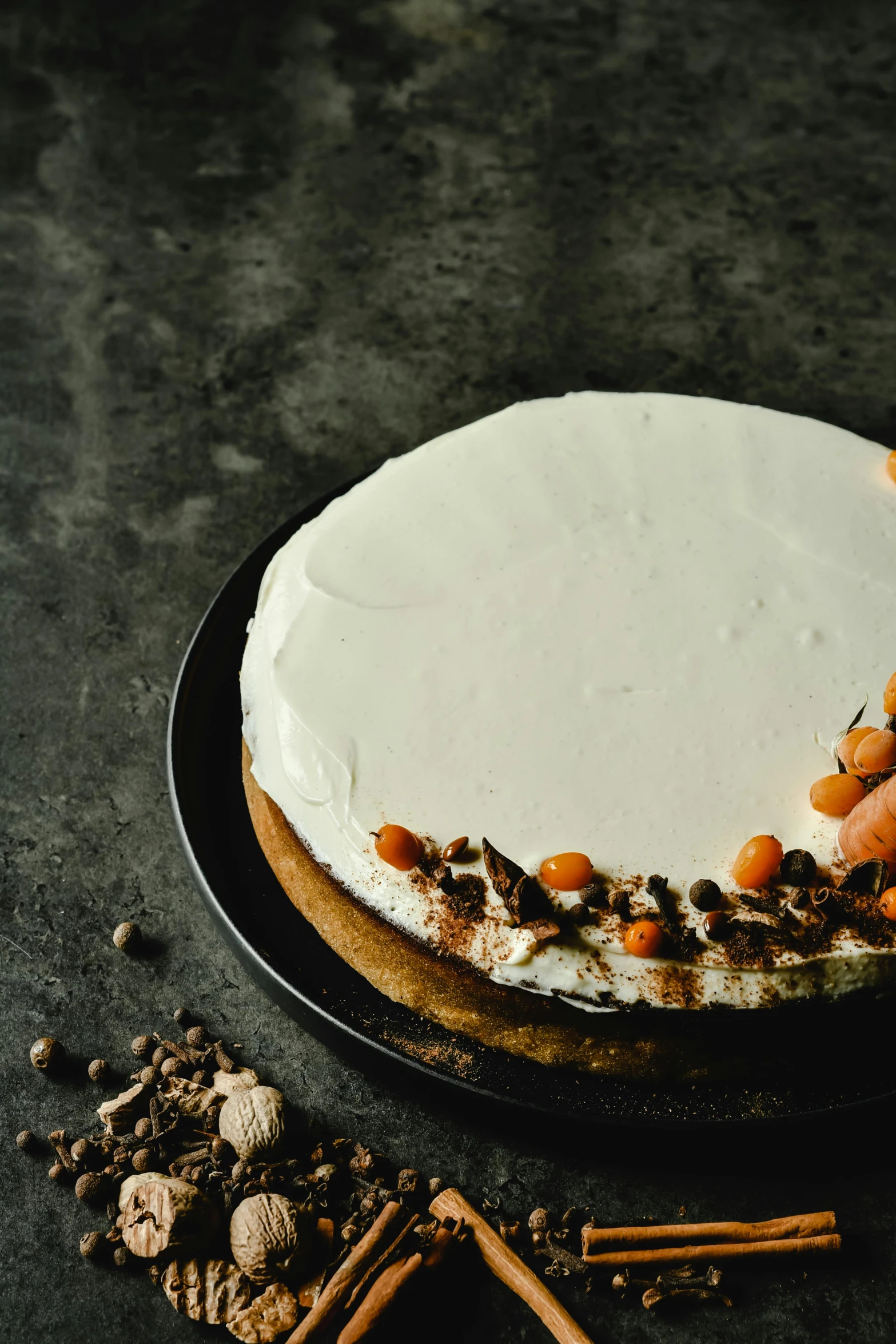 a cake sitting on top of a black plate, by Andries Stock, trending on pexels, figuration libre, white and orange, white with chocolate brown spots, fullbody view, snacks