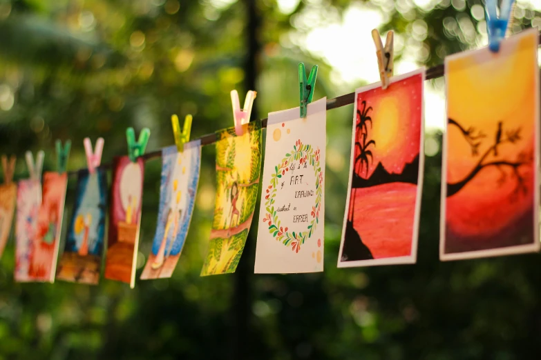 a bunch of pictures hanging on a clothes line, a watercolor painting, pexels contest winner, card art, al fresco, hanafuda, lush surroundings