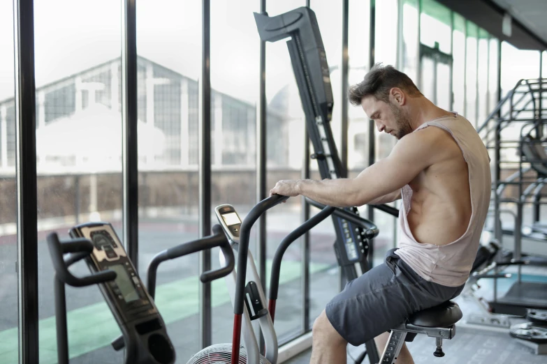 a man sitting on a stationary bike in a gym, by Julian Allen, profile image, 30 year old man :: athletic, avatar image, soft natural light