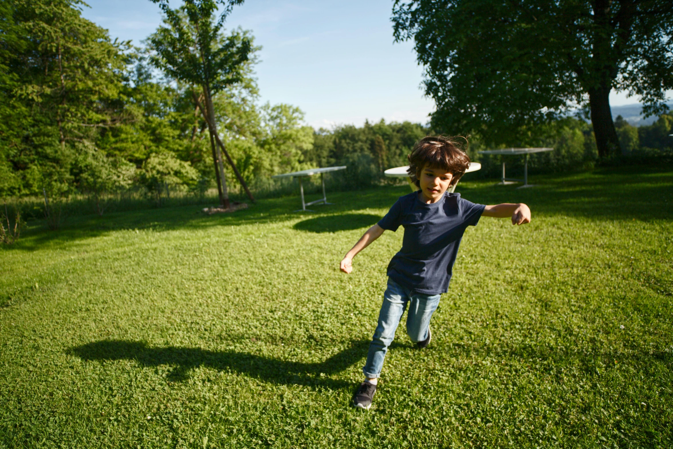 a young boy running across a lush green field, by Sebastian Spreng, pexels contest winner, figuration libre, sunny day time, playing games, in a suburban backyard, wide establishing shot