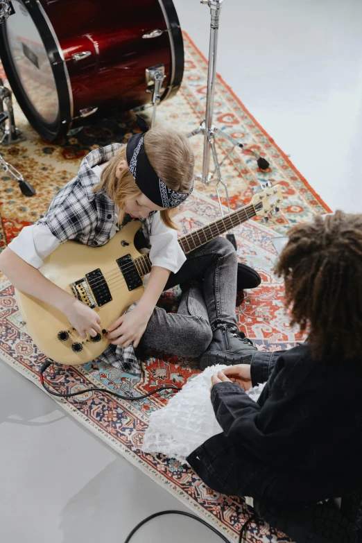 a group of young people sitting on top of a rug, an album cover, trending on pexels, playing electric guitar, little kid, inspect in inventory image, profile pic