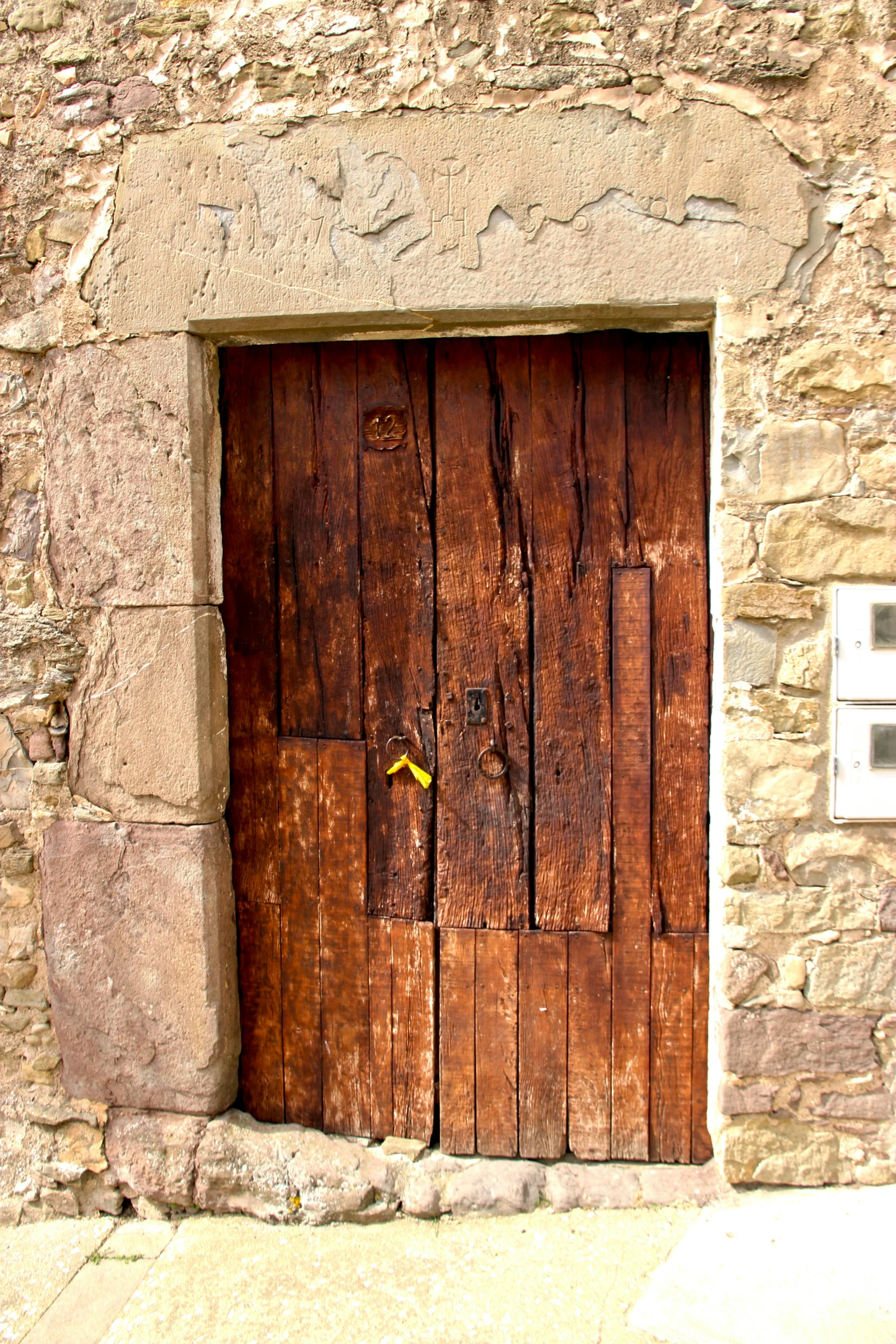 a red fire hydrant sitting in front of a wooden door, an album cover, by Carlo Carrà, renaissance, wood door, pueblo architecture, rugged, stonework