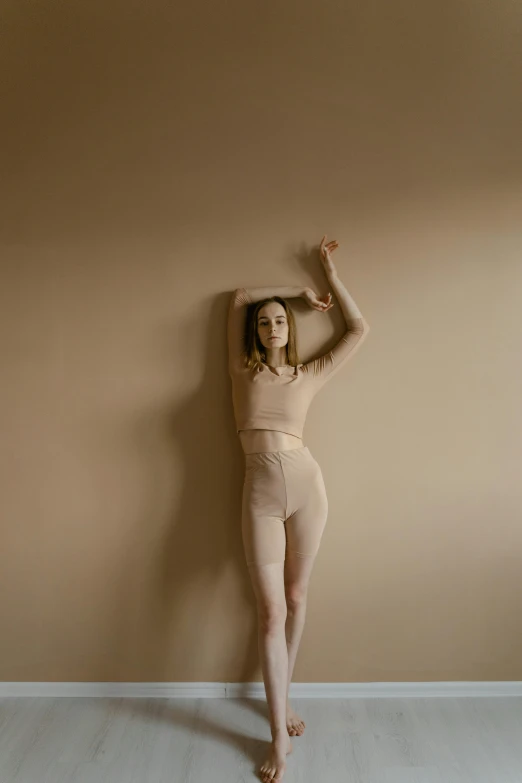 a woman that is standing up against a wall, inspired by Vanessa Beecroft, trending on pexels, arabesque, muted colored bodysuit, pretty face with arms and legs, wearing leotard, muted colors. ue 5