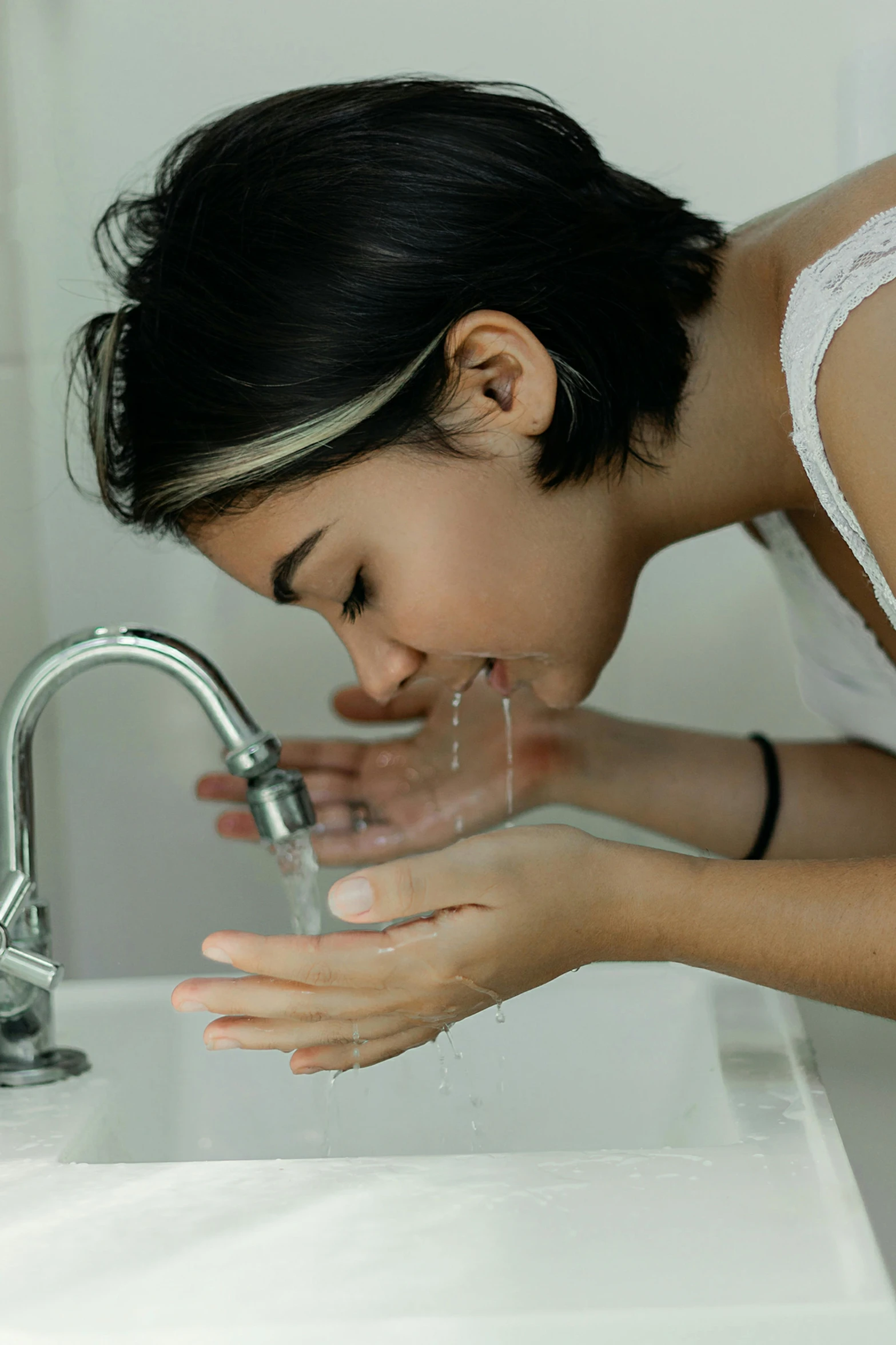 a woman washing her hands in a sink, by Nicolette Macnamara, wide nostrils, teenage girl, malaysian, profile image