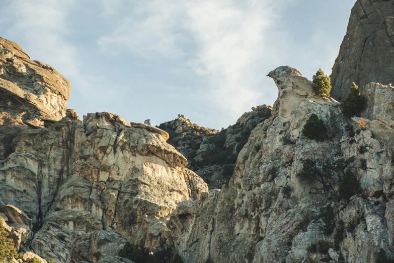 a mountain goat standing on top of a rocky cliff, unsplash, les nabis, wyoming, rock climbers climbing a rock, seen from a distance, mid shot photo