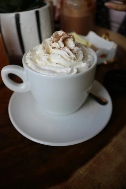 a close up of a cup of coffee on a saucer, whipped cream on top, thumbnail, chile, large)}]