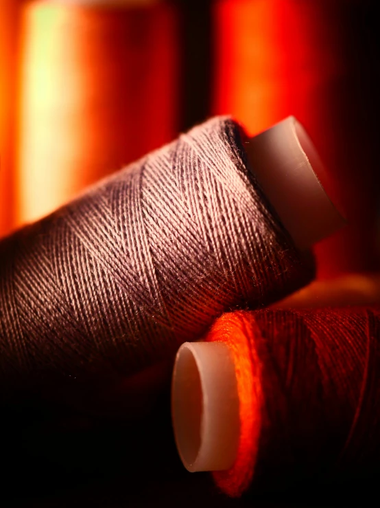 two spools of thread sitting next to each other, a picture, arts and crafts movement, red and orange glow, thumbnail, cinematic shot, brown