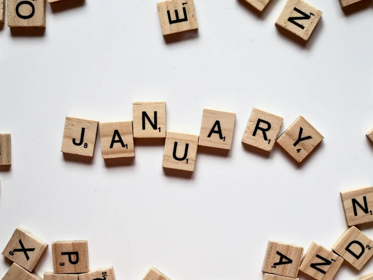 the word january spelled in scrabbles on a white surface, trending on unsplash, happening, 🦩🪐🐞👩🏻🦳, wikimedia commons, placards, pyrography