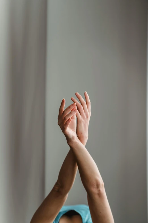 a woman stretching her arms in the air, inspired by Elsa Bleda, trending on pexels, light and space, partially cupping her hands, on grey background, soft indoor light, holding hands