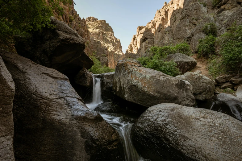 a small waterfall flowing between two large rocks, a portrait, hurufiyya, canyon, carson ellis, 4k photo”, full frame image