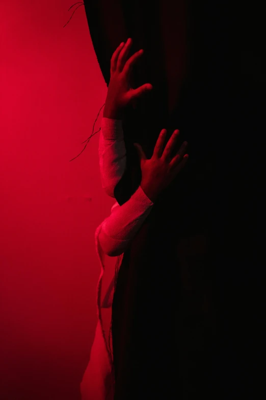 a woman standing in front of a red light, inspired by Nan Goldin, unsplash, conceptual art, hands shielding face, showstudio, red curtain, devils