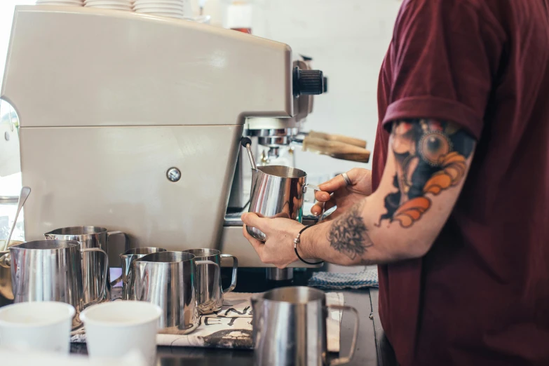 a man that is standing in front of a coffee machine, tattooed, pouring, profile image, instagram post