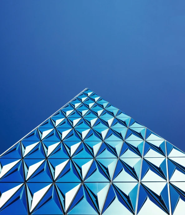 a tall glass building with a blue sky in the background, by Matthias Weischer, unsplash contest winner, crystal cubism, intricate triangular designs, blue and silver colors, futuristic marrakech, square