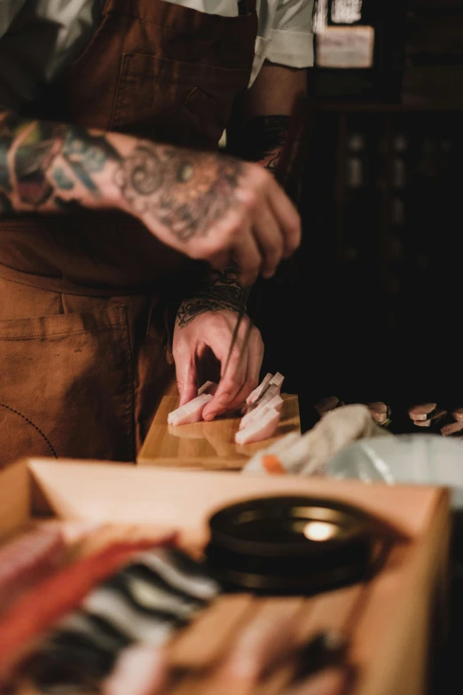 a close up of a person cutting meat on a cutting board, a portrait, by Matt Cavotta, trending on pexels, ukiyo-e, cigarrette boxes at the table, koi, partially cupping her hands, tattooed