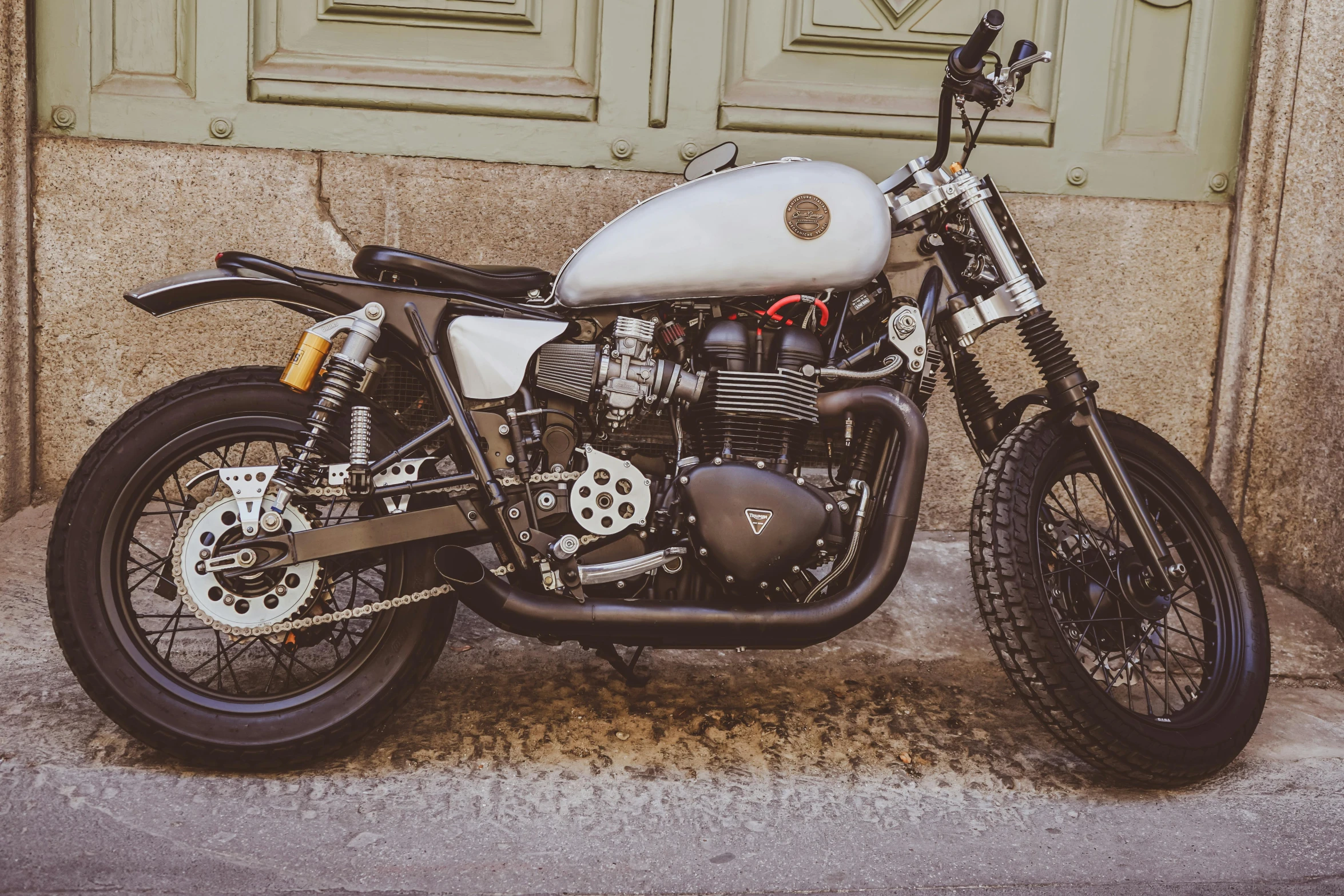 a motorcycle parked in front of a green door, a stipple, pexels contest winner, titanium white, 1 9 5 0 s scrambler, madrid, made from mechanical parts