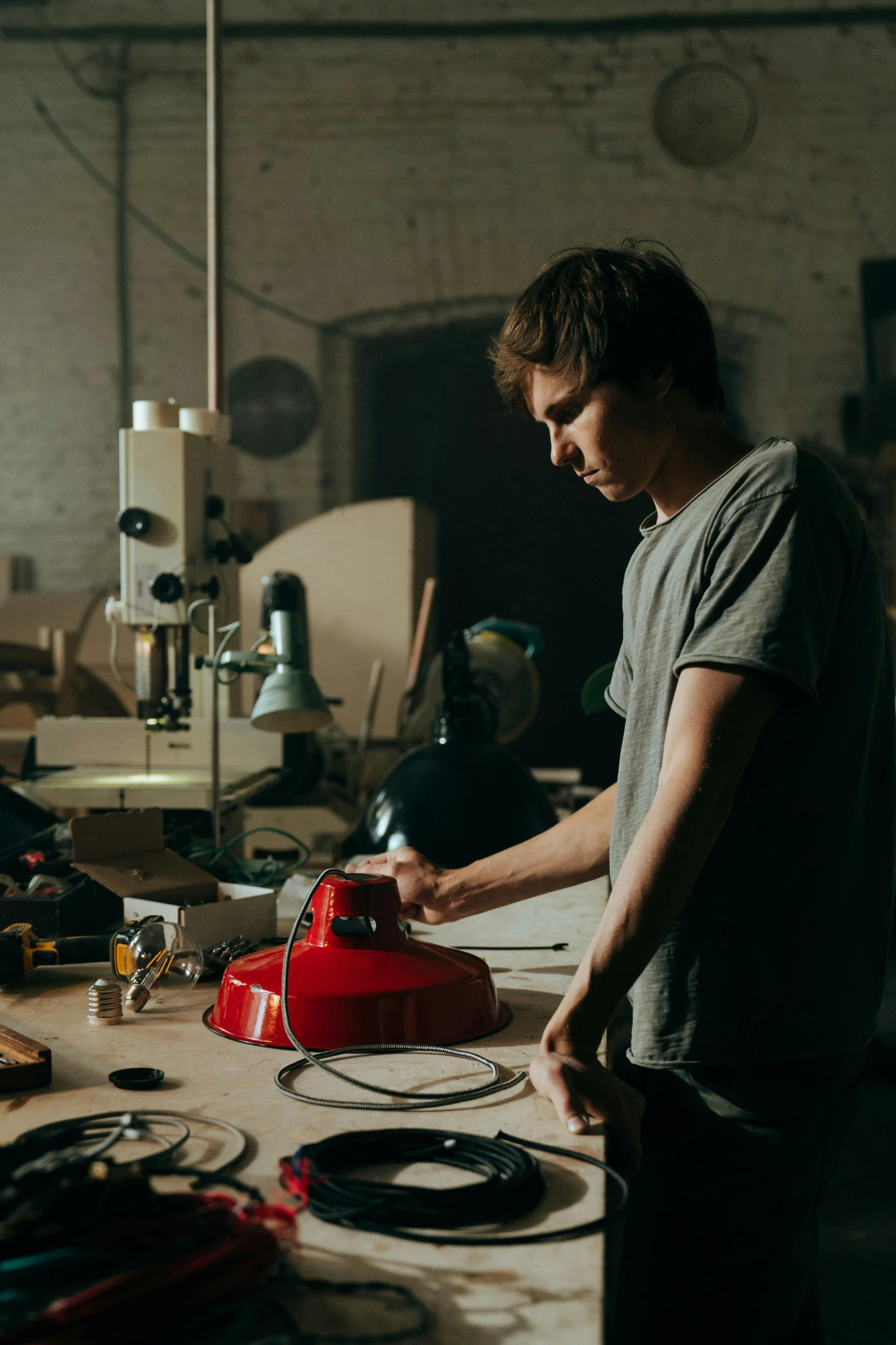 a man working on a piece of wood in a workshop, poster art, by Jacob Toorenvliet, pexels contest winner, portrait of tom holland, holding helmet, lights, bo burnham