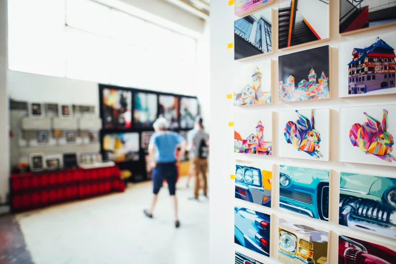 a person walking through a room with pictures on the wall, pexels contest winner, process art, vendors, bright studio setting, crisp lines and color, a busy arcade