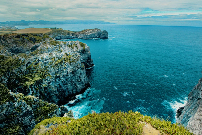 a man standing on top of a cliff next to the ocean, by Simon Marmion, pexels contest winner, vallejo, panoramic, kahikatea, thumbnail