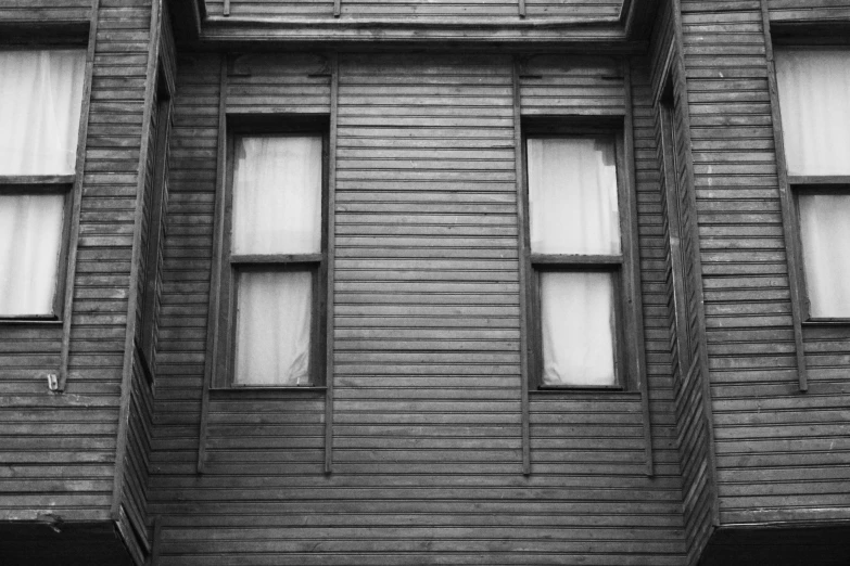 a black and white photo of a building, a black and white photo, inspired by Vivian Maier, pexels, wooden house, bay window, haunted house, 1900s photo