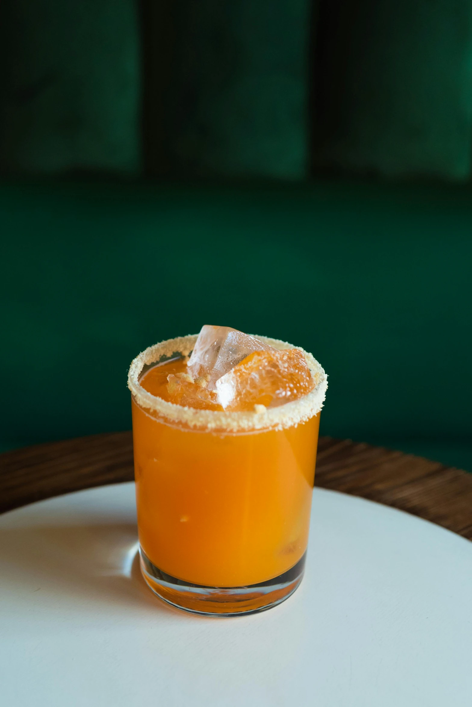 a close up of a drink in a glass on a table, agent orange, emerald, thumbnail, three quarter angle