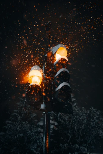 a street light covered in snow at night, pexels contest winner, realism, fire particles, orange lights, stacked image, snowflakes falling