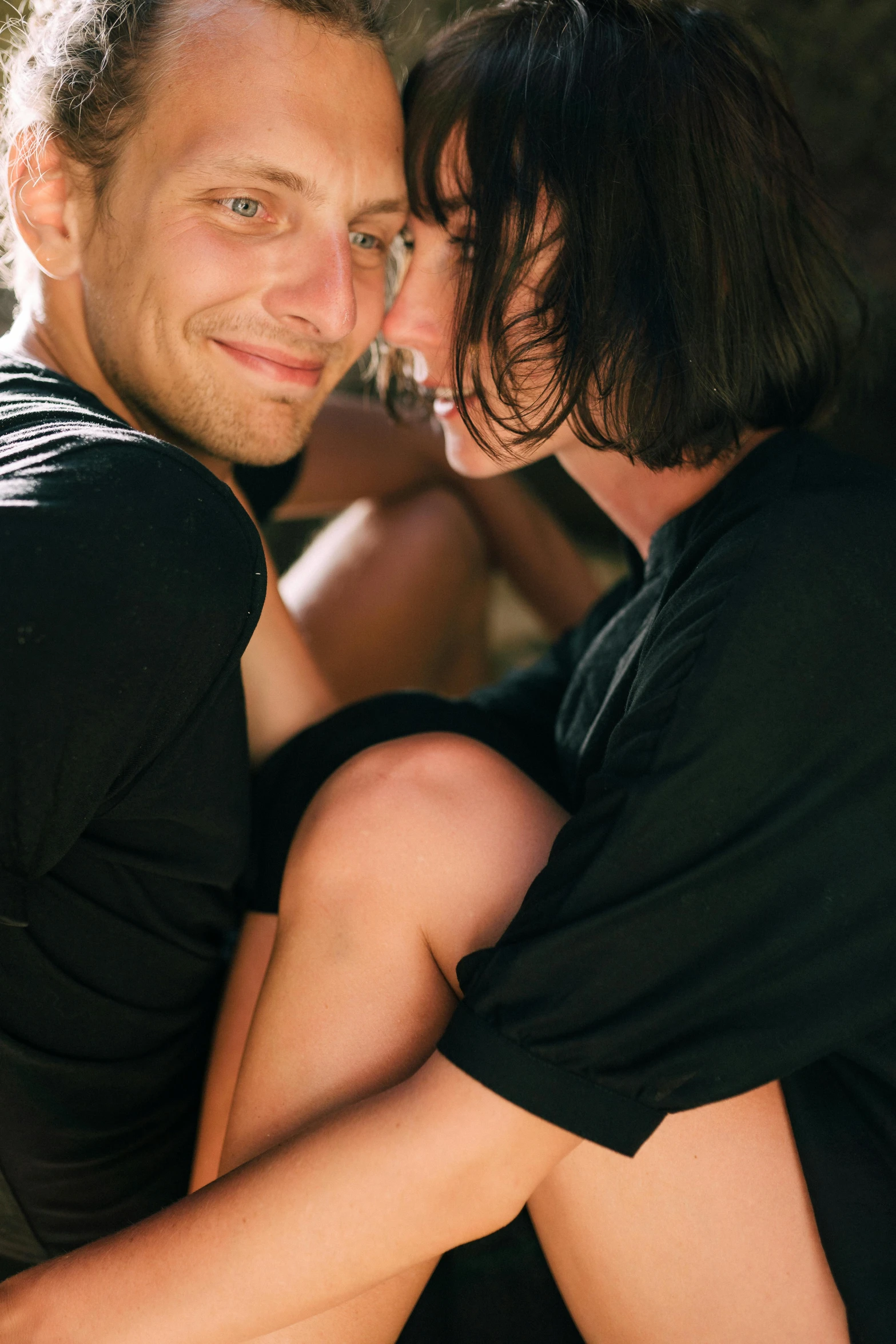 a man and a woman hugging each other, non binary model, bottom angle, smiling, close-up photograph