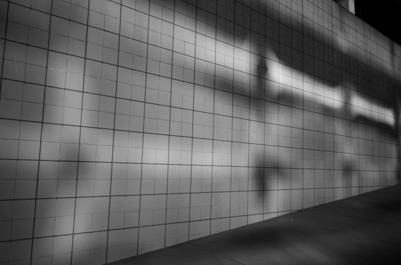 a man riding a skateboard up the side of a wall, a black and white photo, inspired by Peter Basch, montage of grid shapes, long exposure photo, tiles, in a subway