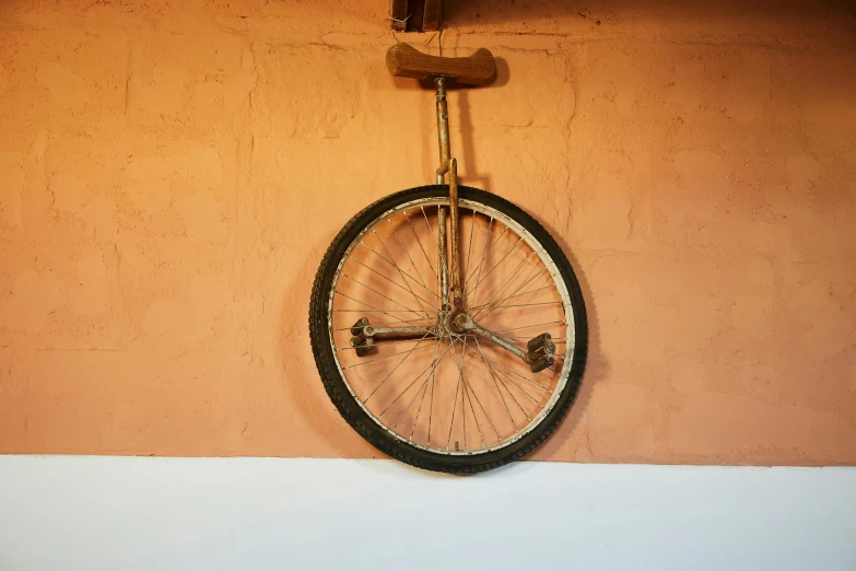 a bicycle wheel hanging on the side of a wall, by Matthias Stom, circus, patina, mid-30s, tripod