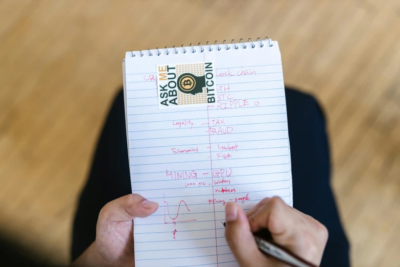 a person holding a pen and writing on a piece of paper, an album cover, by Alison Watt, art brut, algebra, schematic in a notebook, in a workshop, top-down shot