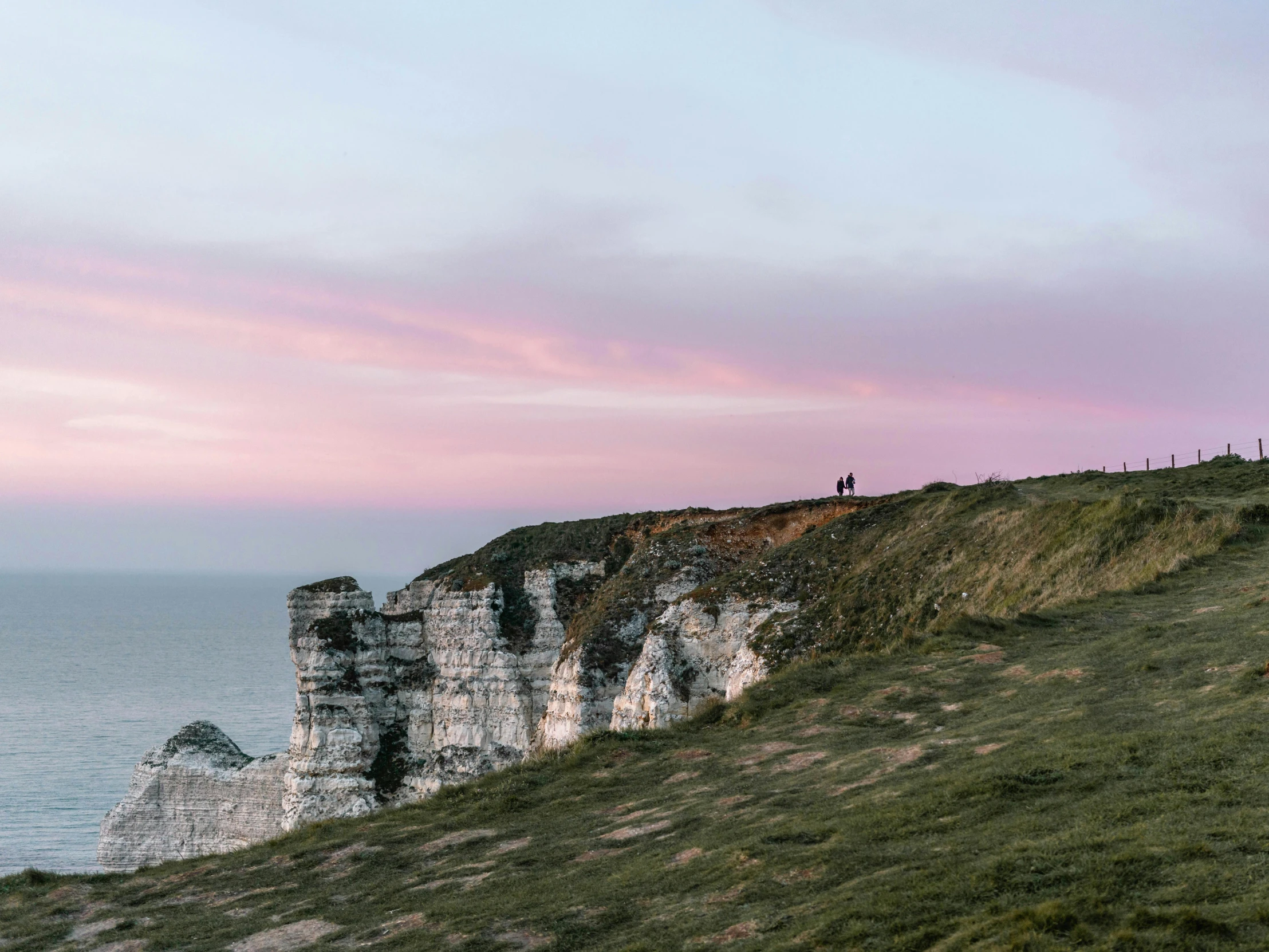 a couple of people standing on top of a cliff, by Daniel Seghers, unsplash contest winner, romanticism, normandy, pink hues, marsden, early evening