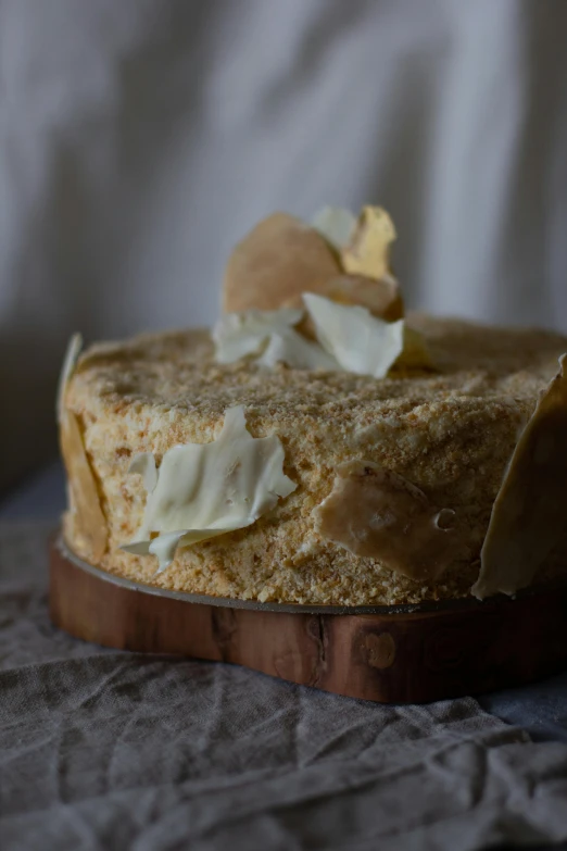 a cake sitting on top of a wooden cutting board, a portrait, unsplash, wearing wheat yellow gauze, ruffled wings, marshmallow graham cracker, detailed product image