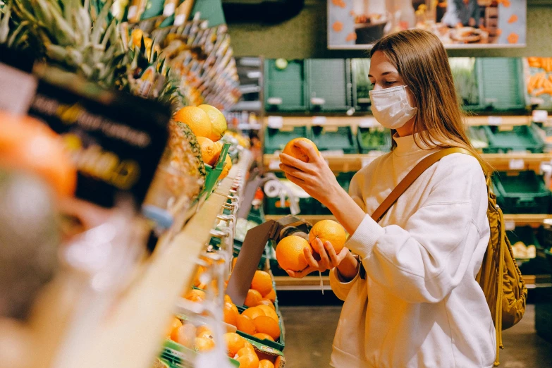 a woman wearing a face mask in a grocery store, by Julia Pishtar, pexels, holding a tangerine, 🦩🪐🐞👩🏻🦳, white and orange, avatar image