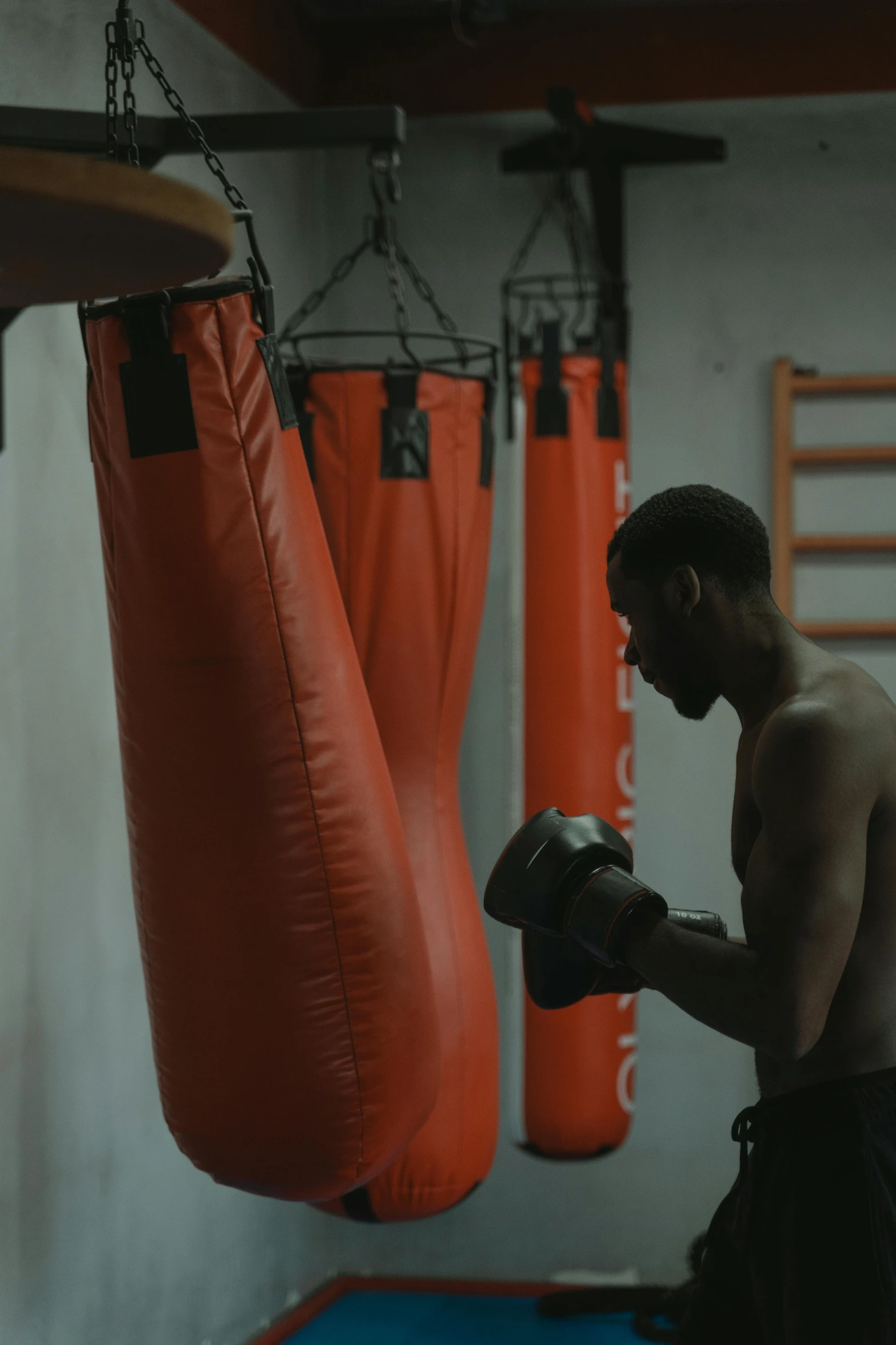 a man standing next to a punching bag, happening, headspace, man is with black skin, shot with sony alpha, orange gi