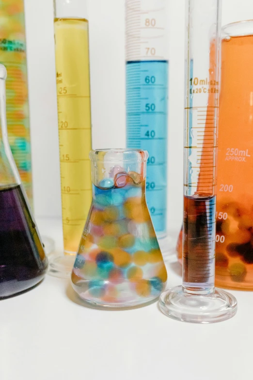a group of different colored liquids sitting next to each other, analytical art, tools for science research, marbles, beaker, working in her science lab