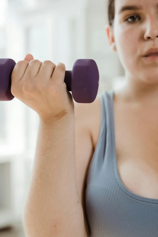 a woman holding a pair of purple dumbs, a colorized photo, trending on pexels, lifting weights, an obese, bruised, do