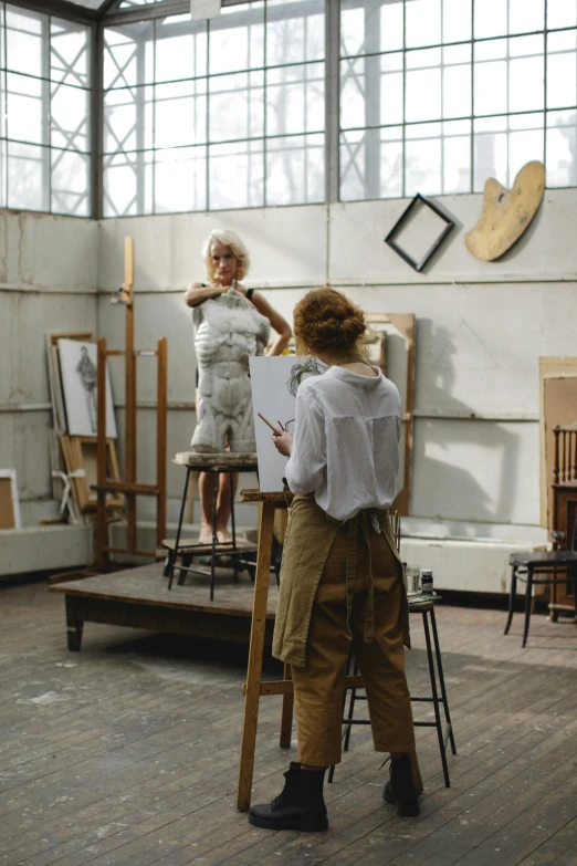 a couple of women standing next to each other in a room, inspired by Carel Willink, trending on pexels, academic art, stands at a his easel, 15081959 21121991 01012000 4k, atelier olschinsky, in a white boho style studio