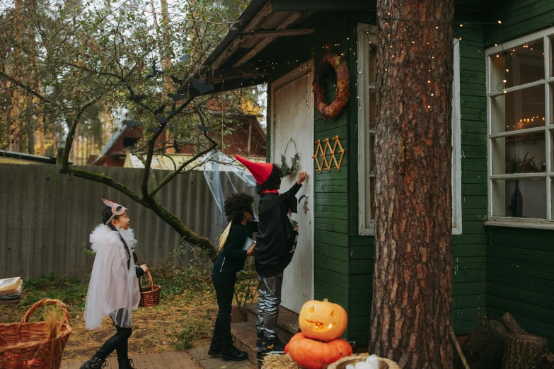 a couple of people that are standing in front of a house, by Julia Pishtar, pexels contest winner, trick or treat, forest themed, about to enter doorframe, kids playing