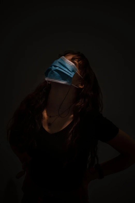 a woman wearing a blindfold in the dark, an album cover, inspired by Elsa Bleda, unsplash contest winner, hyperrealism, medical mask, blue light, cardboard, respirator