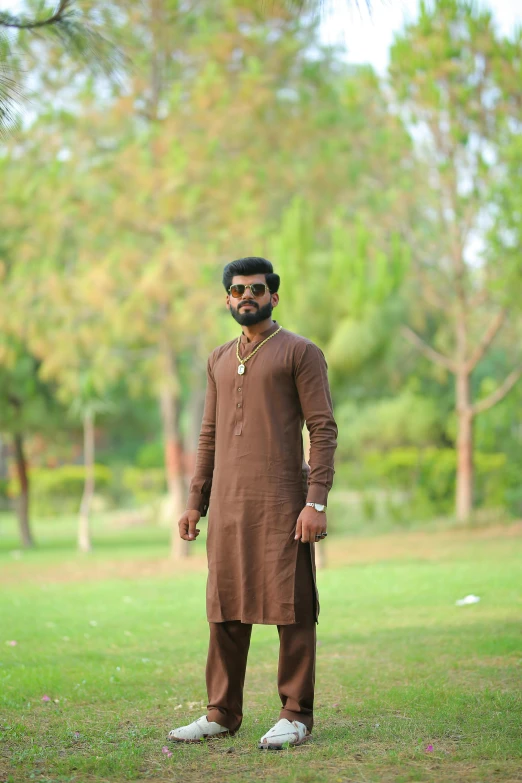 a man standing on top of a lush green field, a picture, by Riza Abbasi, wearing a kurta, brown color, trending photo, brown:-2