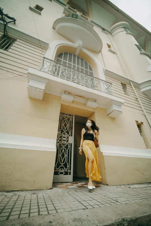 a woman standing in front of a building, pale yellow walls, in style of lam manh, neoclassic, street photo