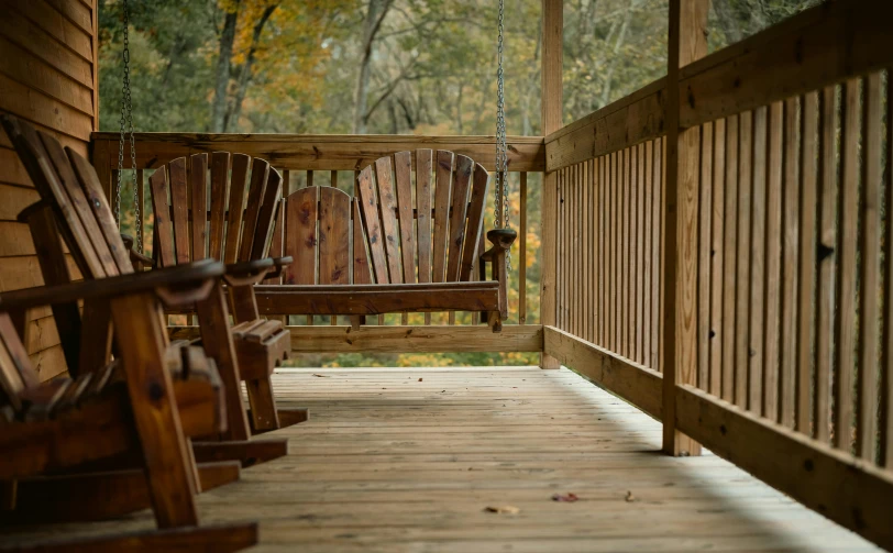 a couple of wooden rocking chairs on a porch, by Linda Sutton, unsplash, william penn state forest, swings, on wooden table, paul barson