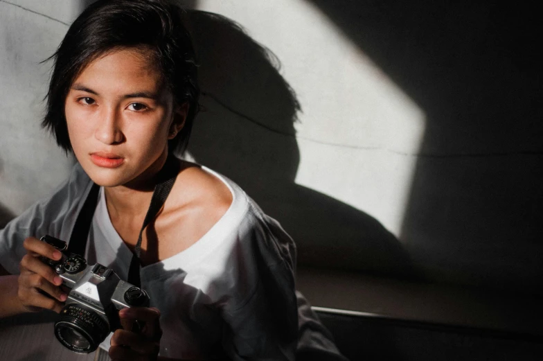 a close up of a person holding a camera, pexels contest winner, photorealism, portrait of modern darna, warm lighting with cool shadows, androgynous person, shooting pose