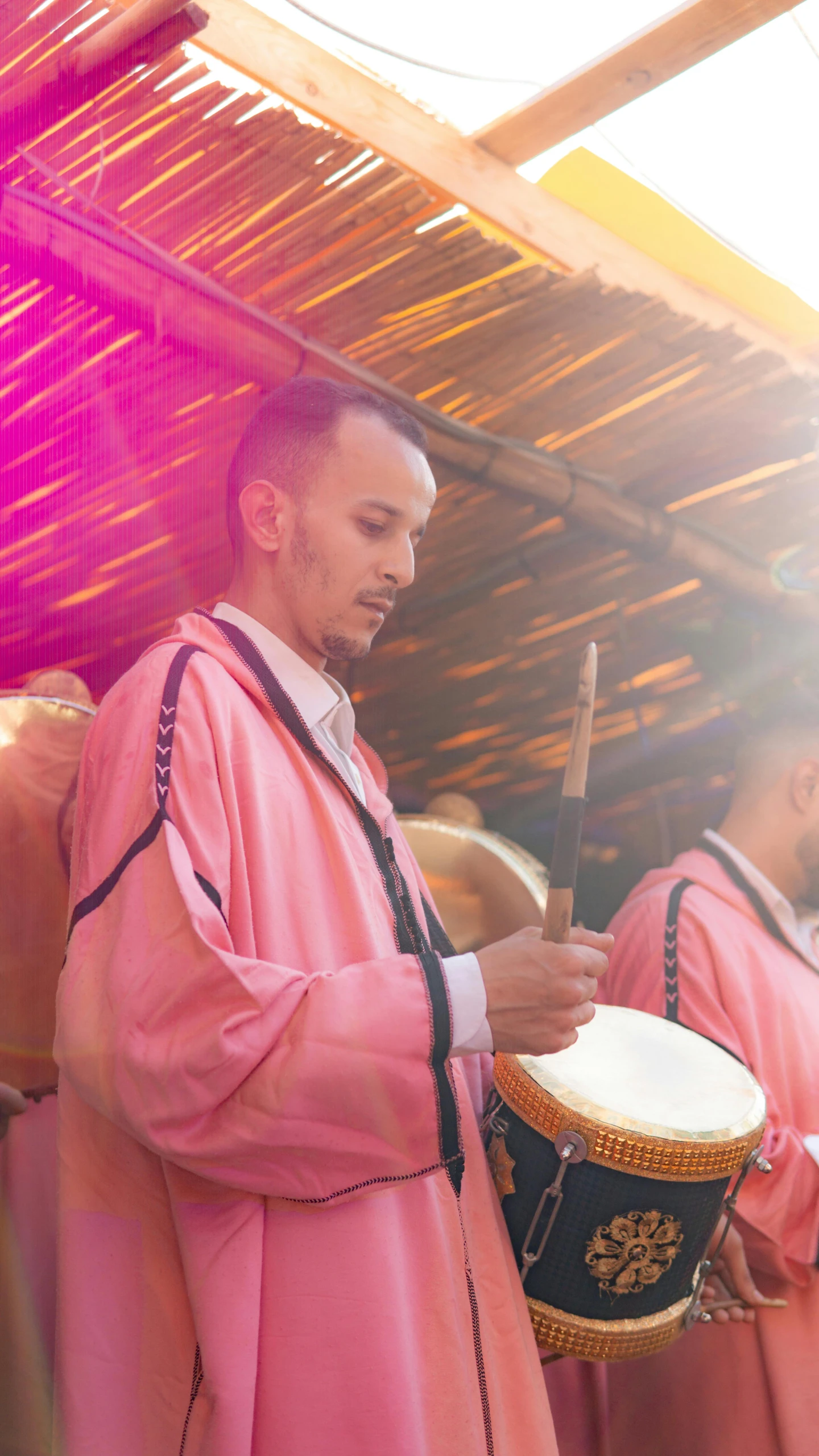 a group of men standing next to each other holding drums, an album cover, pexels, hurufiyya, pastel pink robes, marrakech, live performance, thumbnail