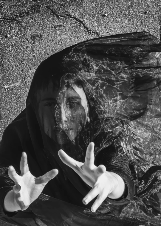 a black and white photo of a man with his hands in the air, a black and white photo, by Jan Rustem, pexels contest winner, surrealism, the eyes of sharbat gula, in a black chiffon layered robe, portrait of a woman underwater, with cobwebs