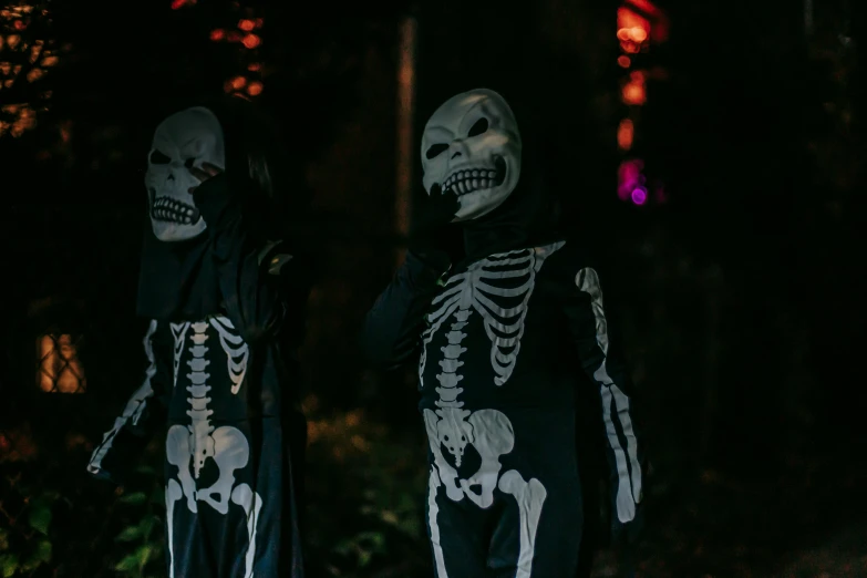 a couple of skeletons standing next to each other, pexels contest winner, antipodeans, trick or treat, dark outside, twins, looking threatening
