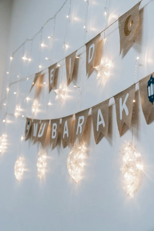 a string of lights hanging from a wall, inspired by Ernő Bánk, hurufiyya, lit. 'honored ka'bah'), white backdrop, party, entertaining